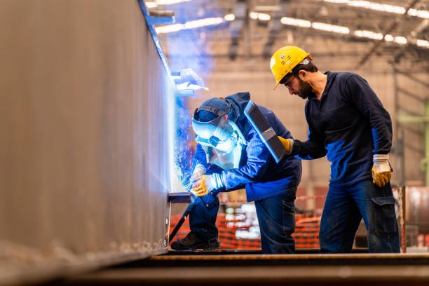 Engineer Teaching Apprentice To Use Welding Machine